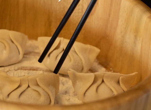 Dumplings en un bowl de madera tomados con palillos